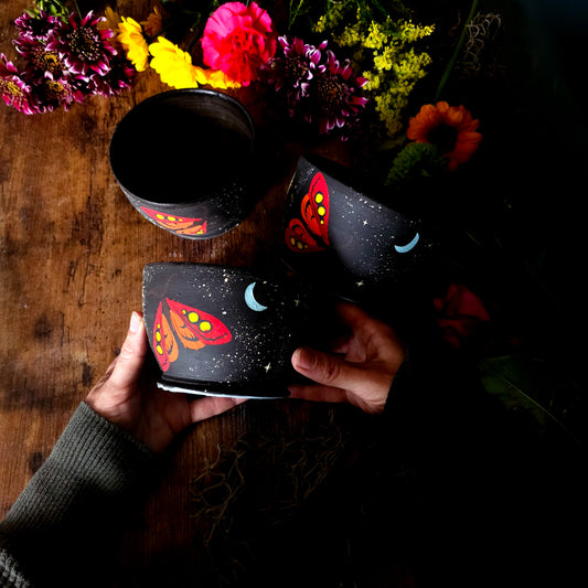 Hand-painted black ceramic bowl featuring colorful moths, tropical leaves, and starry night sky – dark cottagecore aesthetic